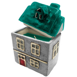Cello Home ceramic scented candle in grey with green roof accents and cut-out windows, porcelain house candle for cosy home décor.