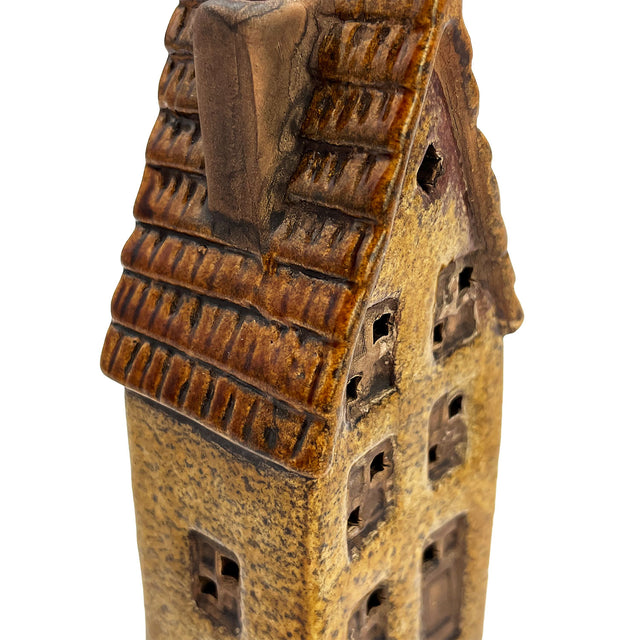 Close-up of the Cello Clockmaker’s Haven ceramic village house showing intricate window details and the warm amber LED light inside.