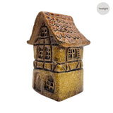 Side view of the Cello Tales from the Village Briarwood Hollow yellow ceramic tealight house showing detailed brick texture and curved tiled roof.