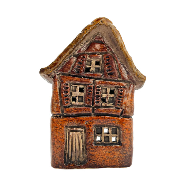 Front angle of the orange Briarwood Hollow pottery house tealight holder with detailed Tudor-style windows and soft candle glow.