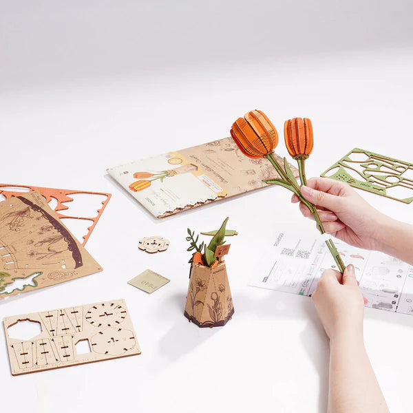 assembling wooden flowers tulip DIY kit with hands placing pieces on craft table