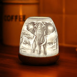 Warm glowing Cello porcelain elephant tealight dome creating ambient light.