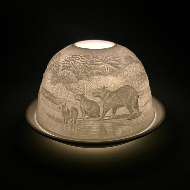 Side view of the Cello capybara porcelain tealight dome glowing softly.