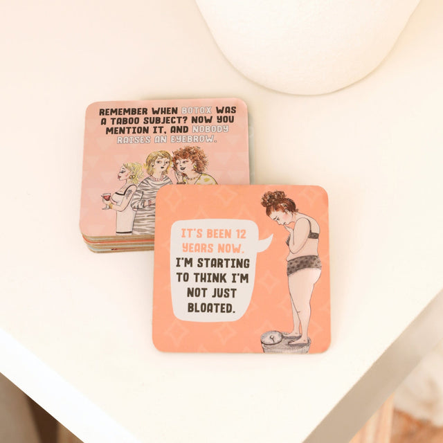 Drinks coasters with humorous designs and text on a white surface.