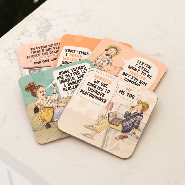 Set of humorous illustrated drinks coasters on a marble surface