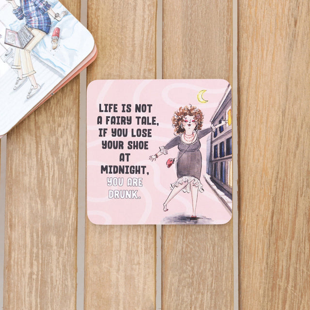 Drinks coasters with illustration of a woman and humorous quote on a wooden surface