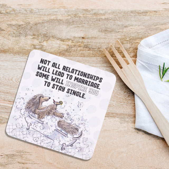 Drinks coasters with a humorous message about relationships on a wooden surface with a fork and container.
