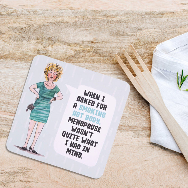 Drinks coasters with a cartoon of a woman in a green dress and humorous text on a wooden surface.