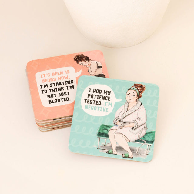 Two humorous drinks coasters with illustrated characters and text on a white surface