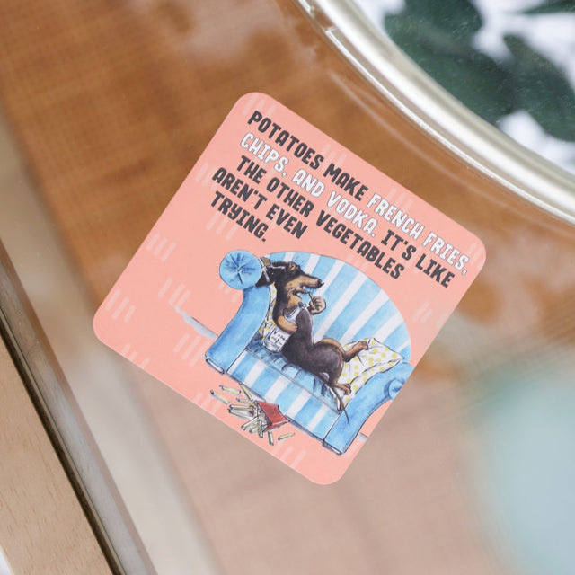 Drinks coasters with a dog illustration and humorous text on a glass surface
