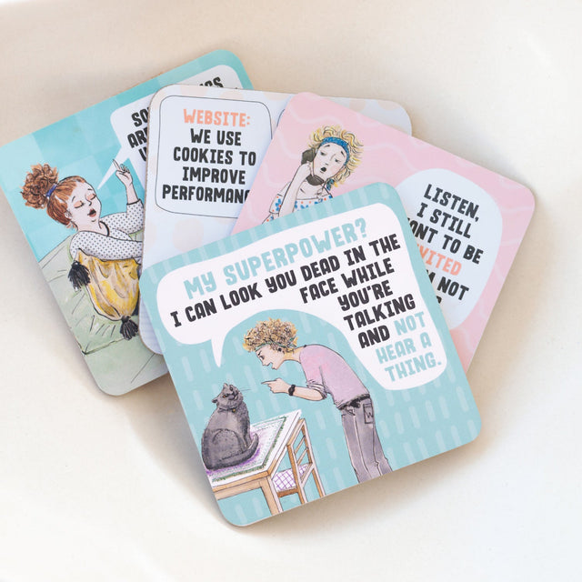 Set of four humorous drinks coasters with illustrations and text on a light background