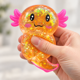 Orange glitter axolotl squishy toy being squeezed by hand