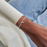 Silver charm bracelet worn on wrist