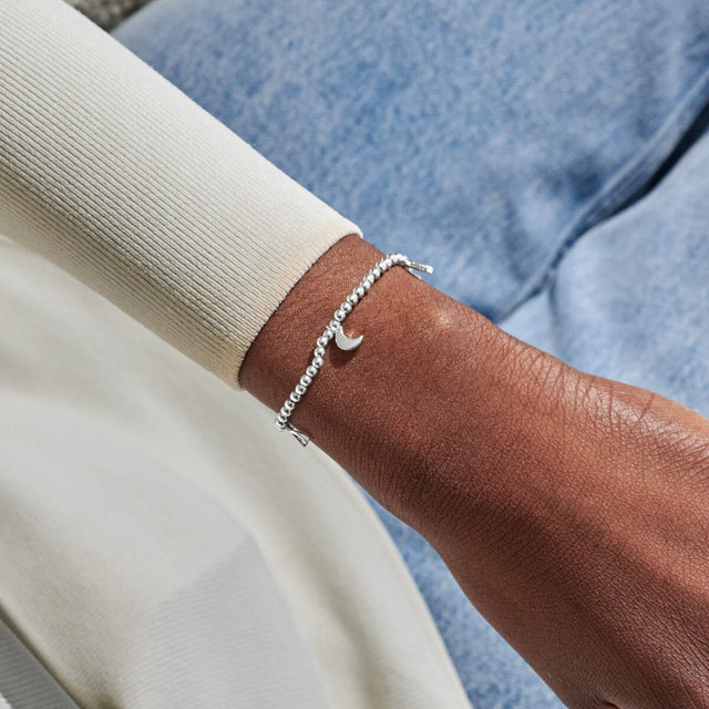 Silver charm bracelet worn on wrist