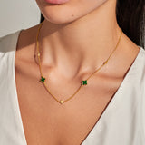 Clover gold necklace with green clover charms worn on neckline