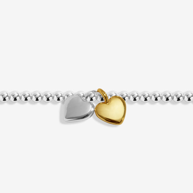 Close-up of silver and gold double heart charms on silver anklet