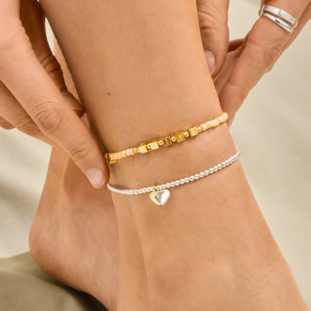 Mixed metal silver and gold heart charm anklet worn for summer styling