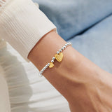 Adult friendship bracelet with silver beads and gold heart charms worn on wrist