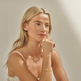 Woman styling gold clover bracelet with matching jewellery