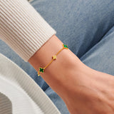 Gold clover bracelet with green clover charms worn on wrist