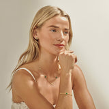 Model wearing gold clover earrings with green detail