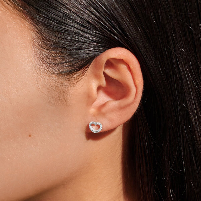 Silver heart earrings worn on ear