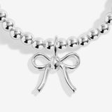 Close-up of the ribbon bow charm on Joma Jewellery's Happy Christmas kids' bracelet