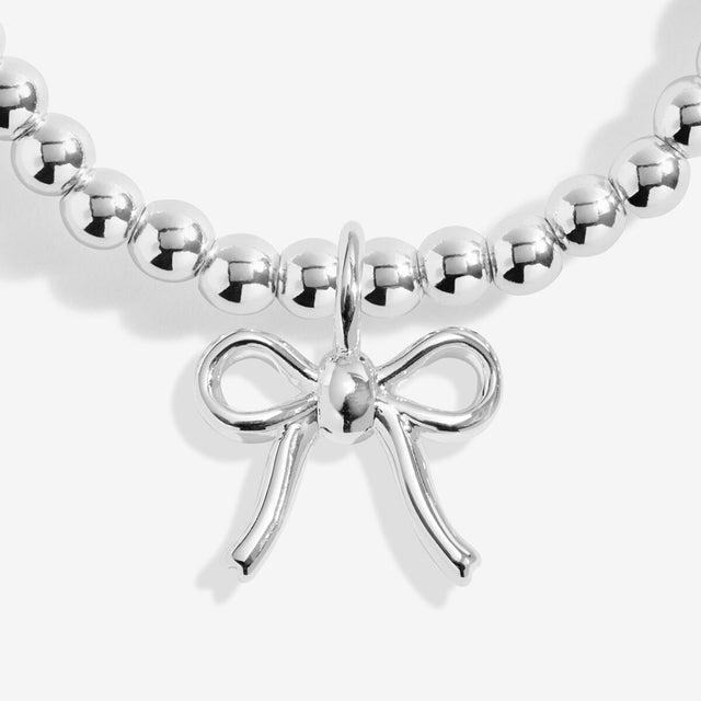 Close-up of the ribbon bow charm on Joma Jewellery's Happy Christmas kids' bracelet