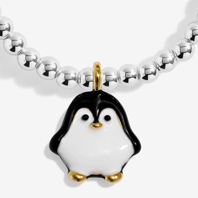 Close-up of the black and white penguin character charm with gold-coloured details on Joma Jewellery's Jomees Snow Cute kids' bracelet