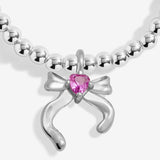 Close-up of the bow charm with a pink heart detail on Joma Jewellery's Merry Christmas Daughter kids' bracelet