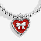 Close-up of the red heart charm with a silver-coloured bow on Joma Jewellery's Merry Christmas Granddaughter kids' bracelet