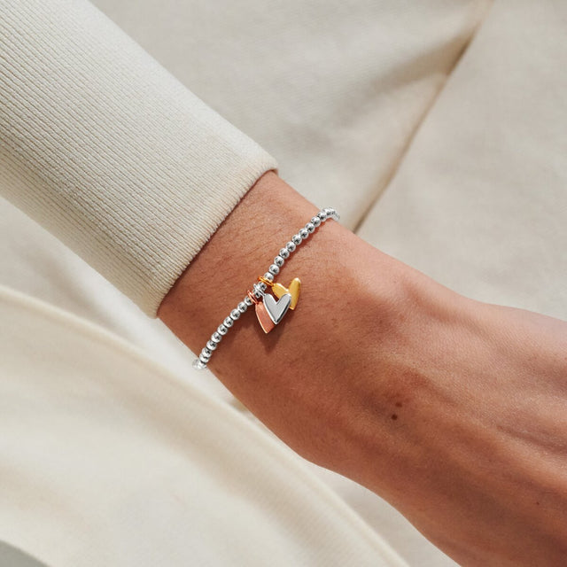 Mixed metal heart charm bracelet worn on wrist