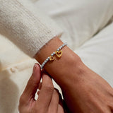 Silver and gold heart charm thank you bracelet worn on wrist