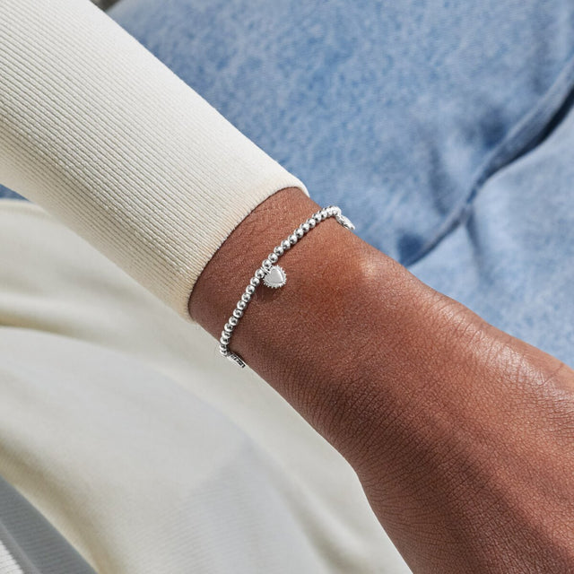 Silver charm bracelet worn on wrist