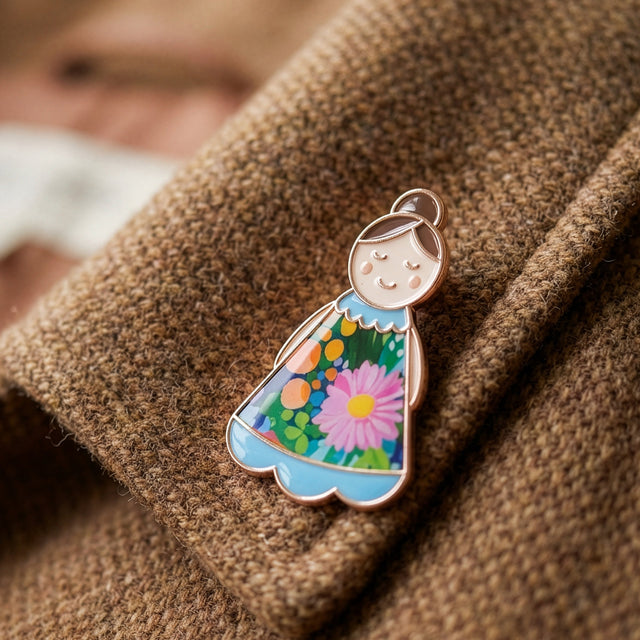 Lucky Little Ladies Mum enamel pin badge gift with floral dress design and rose gold detail worn on jacket lapel.