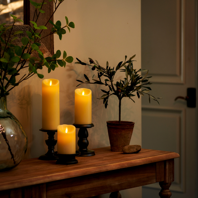 Luminara battery operated ivory candles glowing on a wooden console table