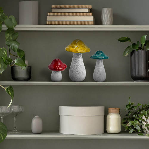 Porcelain decorative mushrooms in varying sizes displayed together on a shelf, hand-crafted with earthy glazes for woodland-inspired home décor