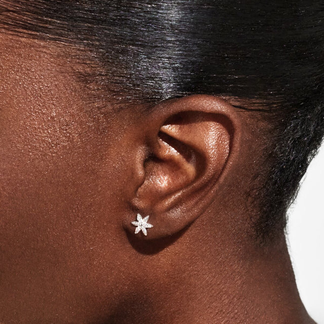 Silver flower stud earrings worn on ear