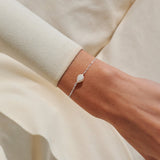 Silver pearl bracelet with heart charm worn on wrist