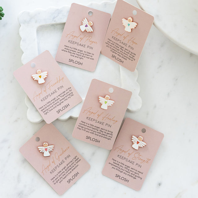 Group of Splosh Angel Keepsake Pins in pink packaging, featuring Angel of Healing and other designs from the collection.