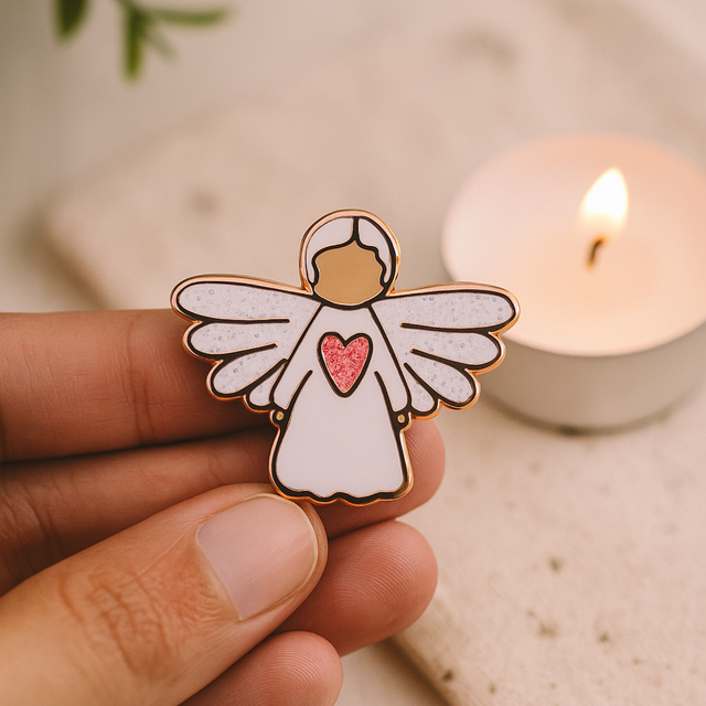 Angel of Guidance guardian angel pin held gently in hand beside a lit candle, symbolising guidance, peace, and faith.