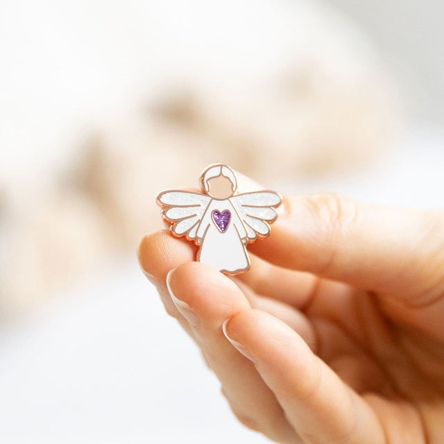 Person holding the Splosh Angel of Prayer Keepsake Pin, showing detailed angel design and soft rose gold finish.