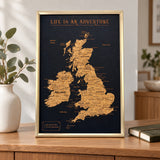 Splosh black UK & Ireland travel map with gold frame standing on wooden furniture in a neutral home setting