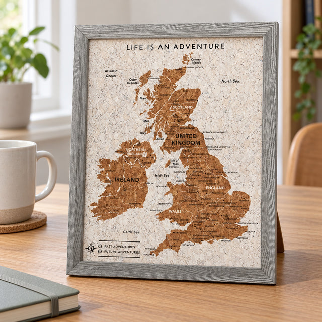 Splosh grey UK & Ireland travel map with grey woodgrain frame, compact map standing on a desk beside a mug