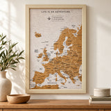 Splosh white Europe travel map with natural wood frame displayed on a wall above wooden furniture
