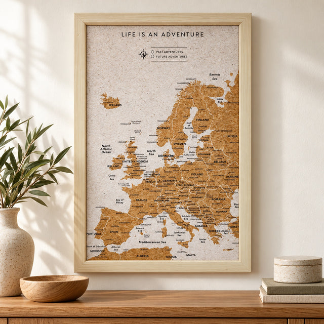 Splosh white Europe travel map with natural wood frame displayed on a wall above wooden furniture