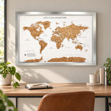 Splosh white World travel map with silver frame displayed on a wall above wooden furniture