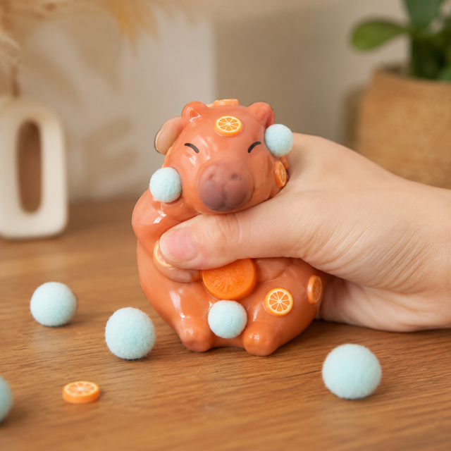 Sticky Capybara fidget toy with soft tactile texture, attached pom poms and orange slices