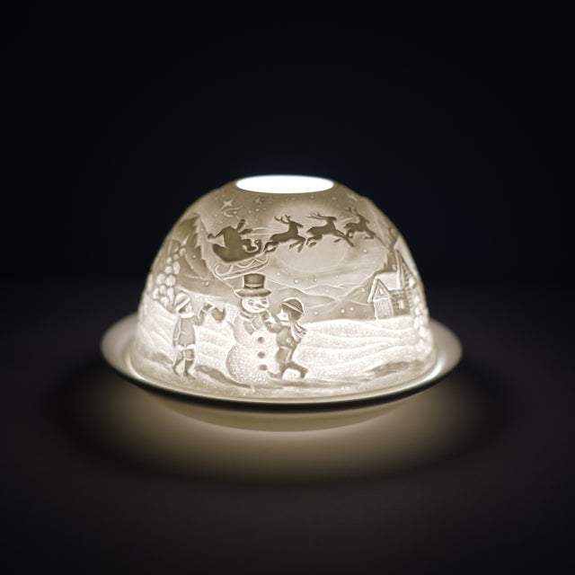 Cello porcelain tealight holder dome, in our snowman design. This design displays a snowman playing with kids next to a house, with Santa flying over in the background. We offer a wide range of porcelain tealight holders to let you choose your show stopping piece and show it off with pride when guests and family are over.  Pick your preferred option between LED lights or using tealight candles. 